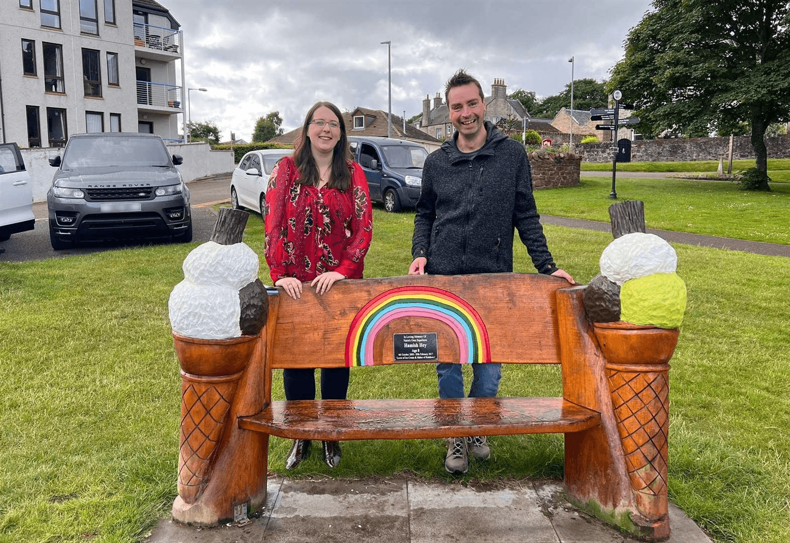 Emma Roddick MSP and Sam from Team Hamish standing behind a colourful ice cream-themed bench with a rainbow on Nairn Links.