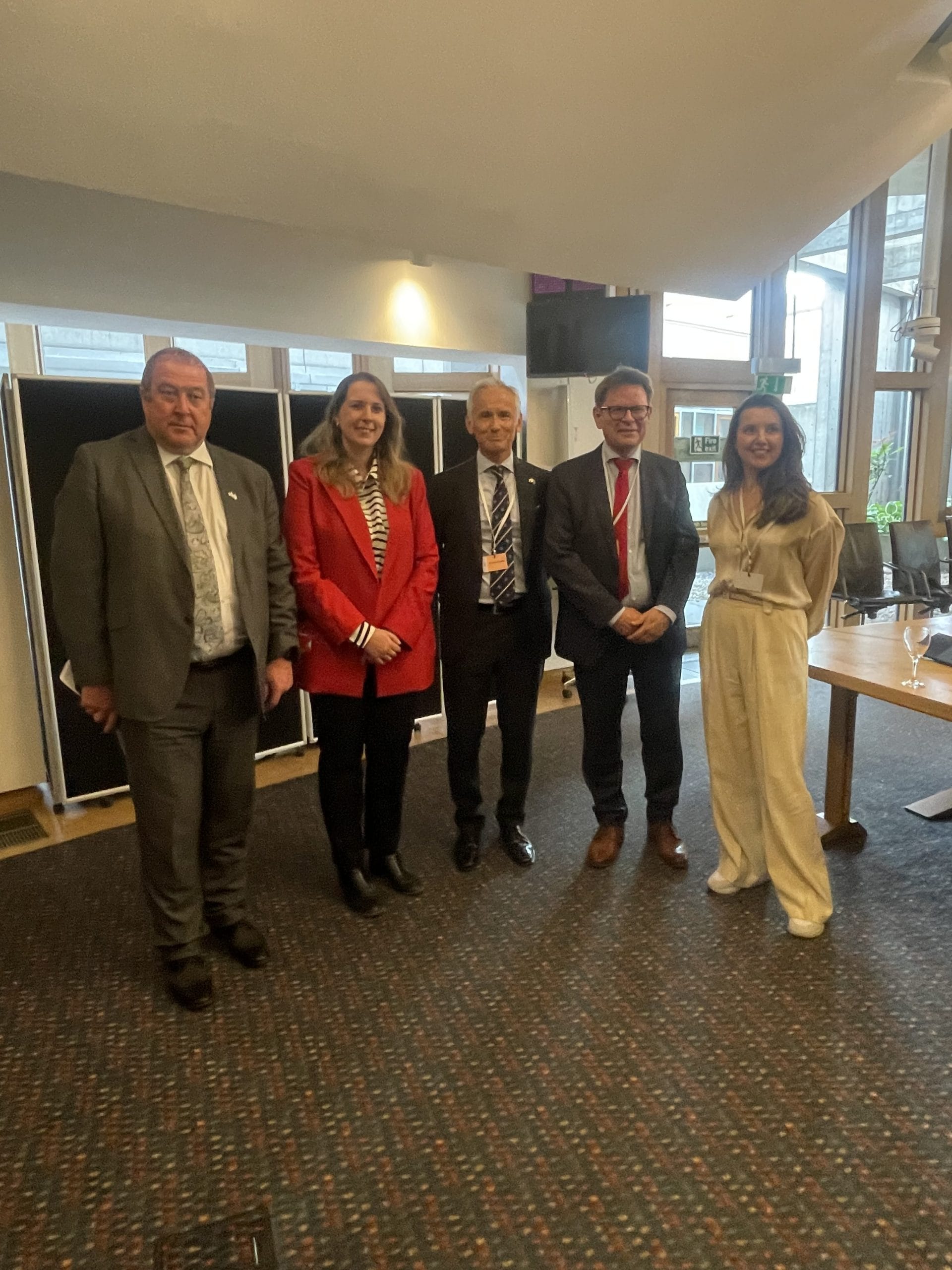 Emma Roddick with Liberation Convoy delegates inside the Scottish Parliament, all smiling for the camera.