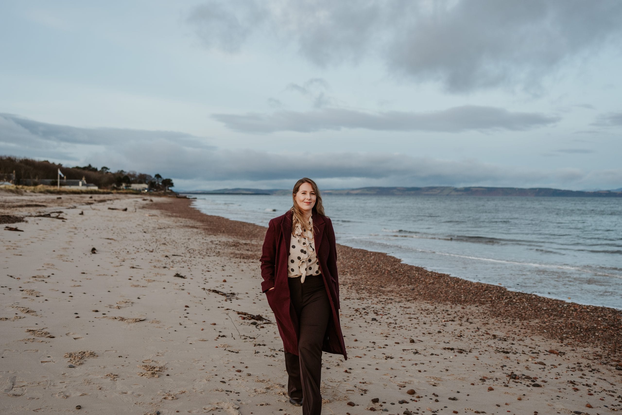 Emma Roddick MSP standing on a windswept beach, looking thoughtful.